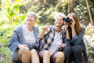 Teenager girl and two grandmother traveling travel to forest and adventure while using binoculars exploration together with happy, senior woman and granddaughter hiking with fun and vitality.