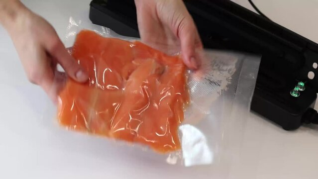 Vacuum packaging of salmon fillet fish for long term storage or Sous vide cooking. Using a vacuum packer for long term food storage. Top view.