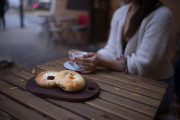 Close-up of woman with cup of coffee and fresh cakes, siting in a cafe.