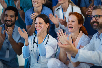 Portrait of happy doctors, nurses and other medical staff clapping in hospital. - obrazy, fototapety, plakaty