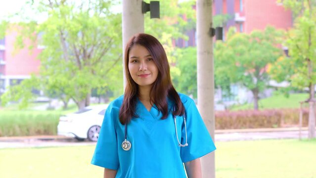 Portrait of a confident, happy, and smiling Asian medical woman doctor or nurse wearing blue scrubs uniform.