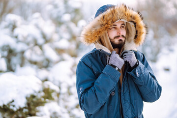 Young man in snowy winter forest. People, lifestyle, relaxation and vacations concept.