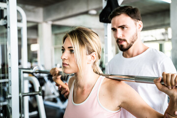 Sport man trainning woman exercise lifting weight in sport gym