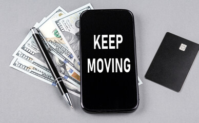 Credit card and text KEEP MOVING on smartphone with dollars and pen. Business
