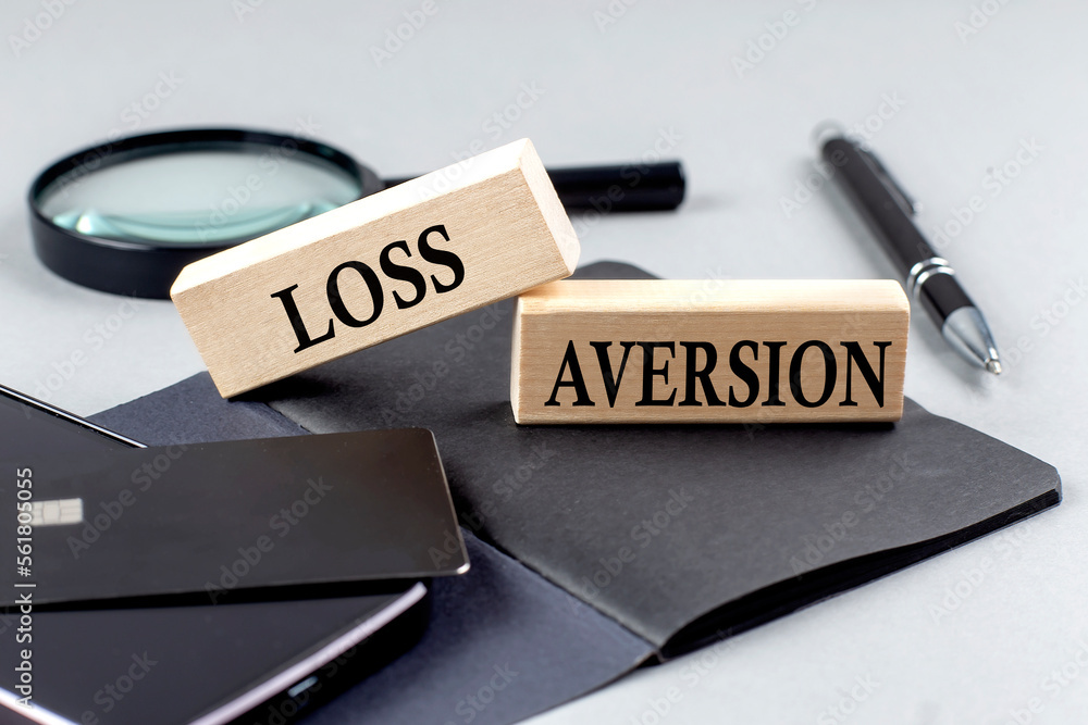 Poster loss aversion text on wooden block on black notebook , business concept