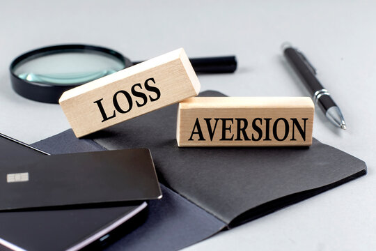 LOSS AVERSION text on wooden block on black notebook , business concept