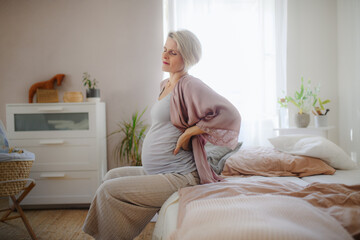 Pregnant woman sitting on her bed and resting.