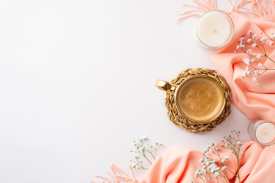 Hello spring concept. Top view photo of cup of frothy coffee on rattan serving mat pink soft plaid candles and gypsophila flowers on isolated white background with copyspace