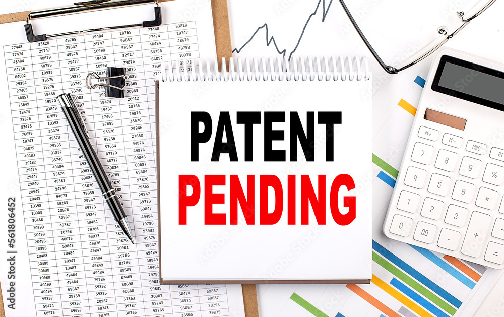 Poster patent pending text on notebook with chart, calculator and pen