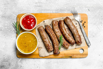 Grill sausages with different sauces .