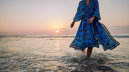 Low section of woman in orient dress enjoying sea. - obrazy, fototapety, plakaty