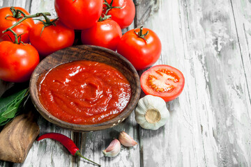 Tomato sauce in bowl and ripe tomatoes.