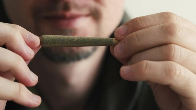 Young man holding marijuana joint in hands. CBD cannabis close up.