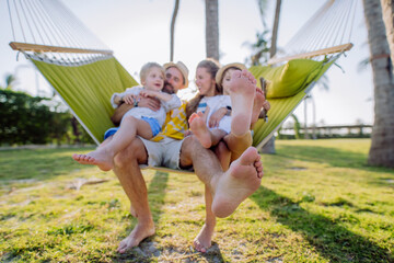 Young family with little kids enjoying their holiday in exotic country, lying in hammock.