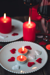Saint Valentine's Day celebration. Red burning candles, hearts, gift box, postcard on dark wooden background. Happy holiday . Table decor for festive dinner, romantic atmosphere