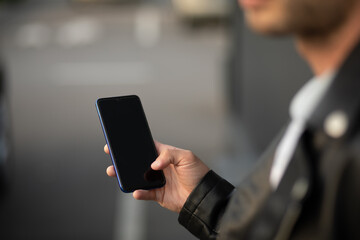 Unrecognizable man holding mobile phone in hand, blurred background