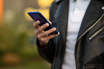 Unrecognizable man holding mobile phone in hand, blurred background