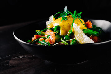 Salad with Boiled Eggs, Salmon, Tomatoes and cucumber in a bowl on black background
