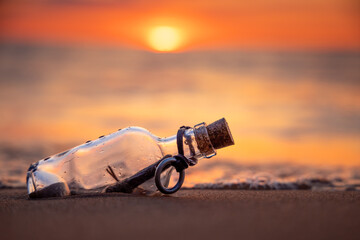 Fototapeta Message in the bottle against the Sun setting down obraz
