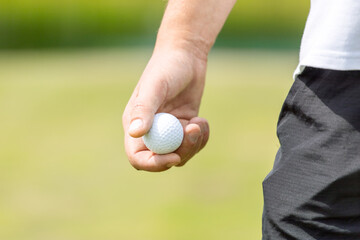 Close up of male golfer's hands holding golf club on green grass. Autumn