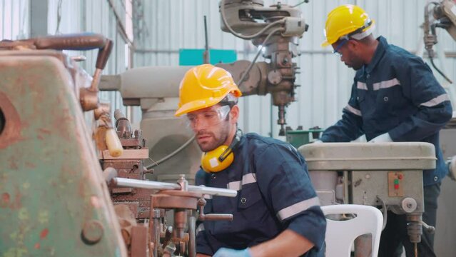 Young caucasian engineer man operating lathe machine for preparing production at factory industrial, technician or labor maintenance machinery at workplace, metalworker working, industry concept.