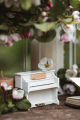 A beautiful postcard. A white piano, a statuette, candles, a book and a vase with a bouquet of...