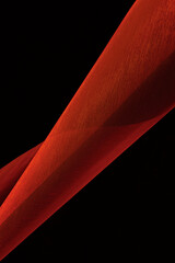 Abstract background. Swirling roll of red satin fabric.Selective focus.
