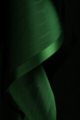Abstract background. Swirling roll of  green satin fabric.Selective focus.