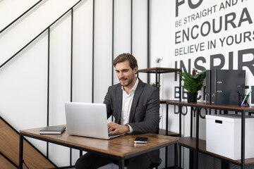 ambitious young successful businessman working on laptop in office