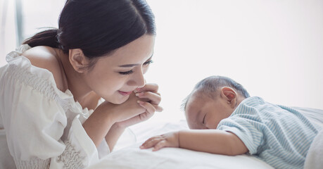 Close up portrait of beautiful young asian mother with her newborn baby, copy space with bed in the hospital background. Healthcare and medical family love lifestyle nursery mother’s day concept