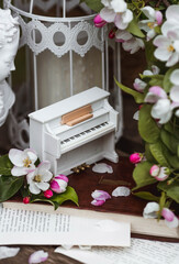 A beautiful postcard. A white piano, a statuette, candles, a book and a vase with a bouquet of...