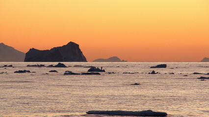 Iceberg silhouetted against an orange sky at sunset at Cierva Cove, Antarctica
