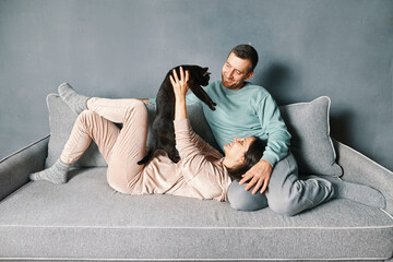 Young couple playing with cat at home