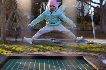 Happy girl child jumping on a trampoline in the street