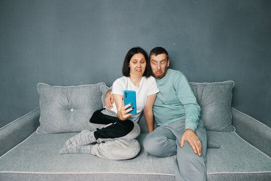 Millennial couple with disgust expression looking at smartphone