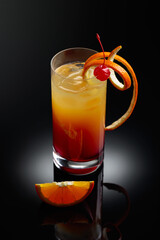 Cocktail tequila sunrise on a black reflective background.