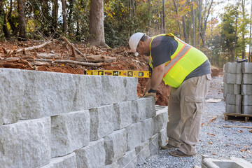 Construction worker building retaining block wall being built on new property