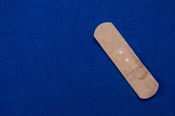Adhesive first aid plaster isolated on blue background. Top view, copy space.