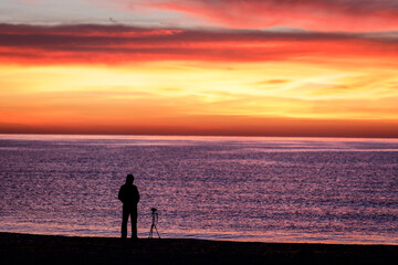 silhouette of a photographer on the beach against sunset