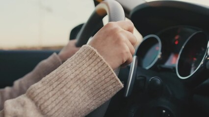 Female hands driver on steering wheel, woman driving the car by road, slow motion. Family trip by car.
