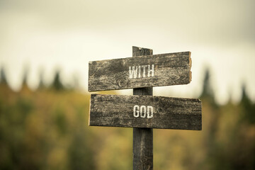 vintage and rustic wooden signpost with the weathered text quote with god, outdoors in nature. blurred out forest fall colors in the background.