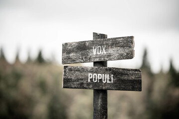 vintage and rustic wooden signpost with the weathered text quote vox populi, outdoors in nature....