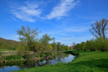 Eine kleiner Fluss in einer idyllischen Landschaft an einem schönen Frühlingstag