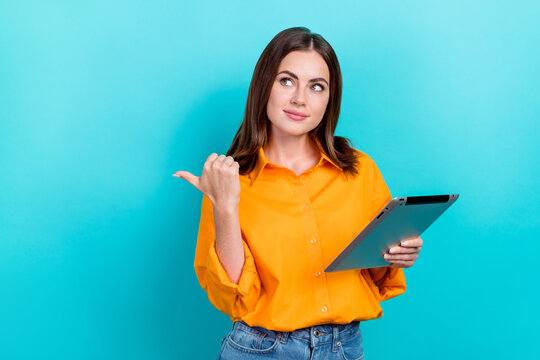 Photo Of Smart Pretty Woman Straight Hairdo Dressed Yellow Shirt Hold Tablet Look Directing Empty Space Isolated On Teal Color Background