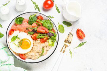 Savory breakfast. Oatmeal porrige with salted salmon, egg and fresh salad. Top view on white table with copy space.