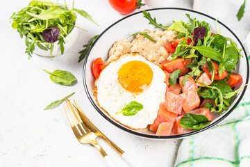 Savory breakfast at white. Oatmeal porrige with salted salmon, egg and fresh salad.