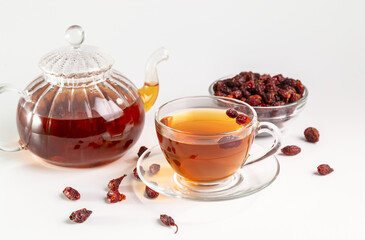 A cup of brewed rosehip medicinal plants herbal tea on a white  table with dried rosehips