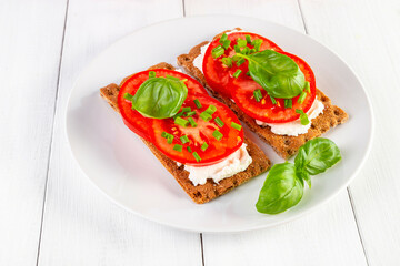 Crispbread with curd cheese, tomatoes, green onions, arugula and basilica. Delicious and healthy breakfast