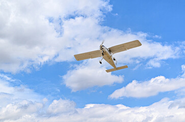 Single engine ultralight plane flying in the blue sky with white clouds	