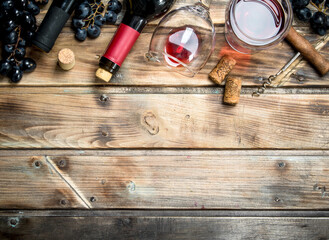Red wine in a glass with grapes and a corkscrew.